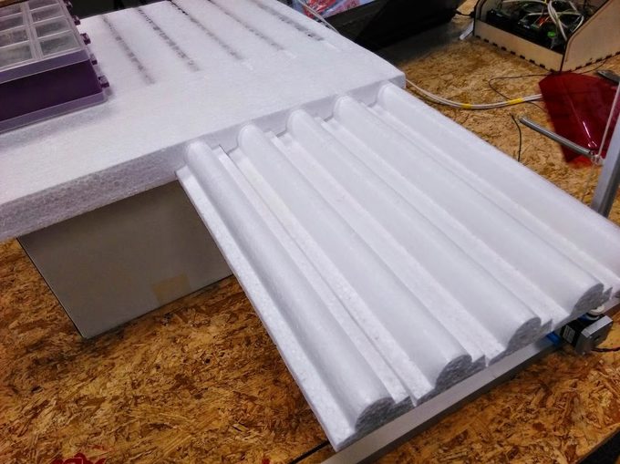 Several parallel bead and half-round moulding profiles cut from a thin EPS sheet on the FoamCube machine bed