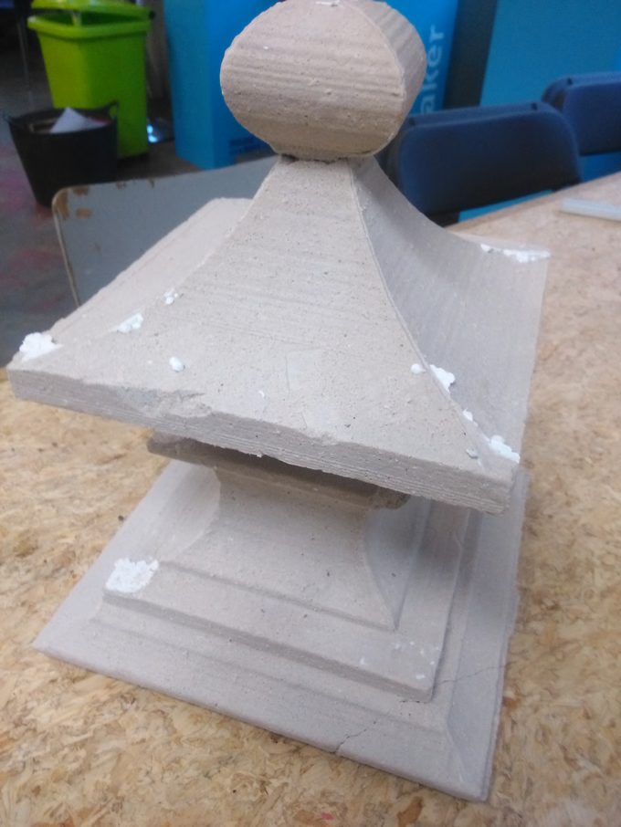 A grey plaster-of-paris finial cast from a hot-wire-cut foam mould, in a makerspace